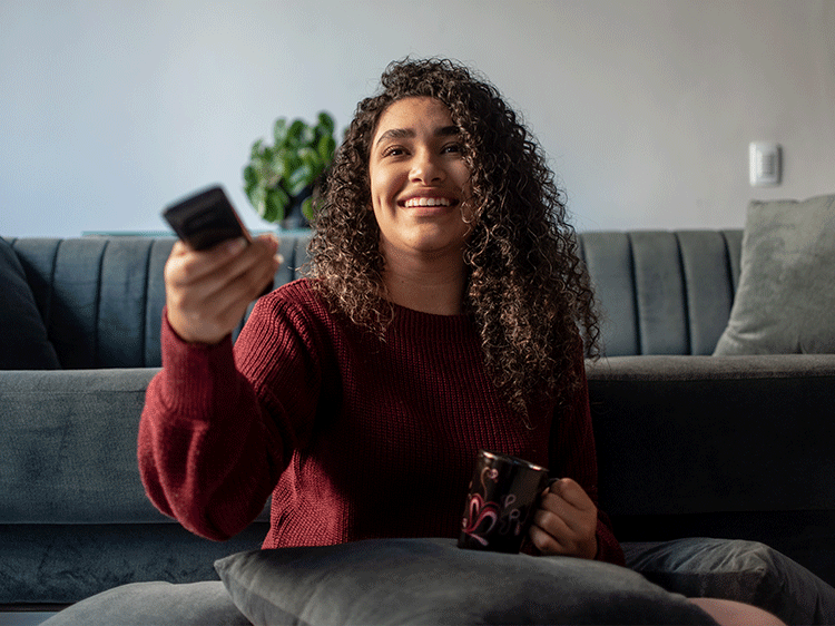 Image of a woman smiling and looking at the television while using her remote
