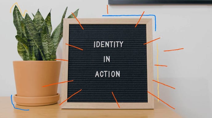 A letter board reads “Identity in Action” beside a potted plant on a table.