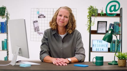 Professional woman sitting at a modern office desk with computer and decor