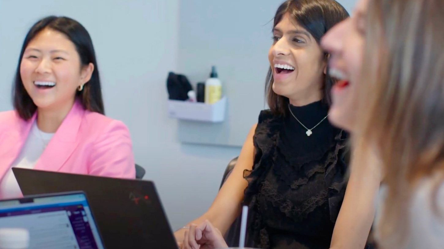 Team members collaborating and laughing during an office meeting
