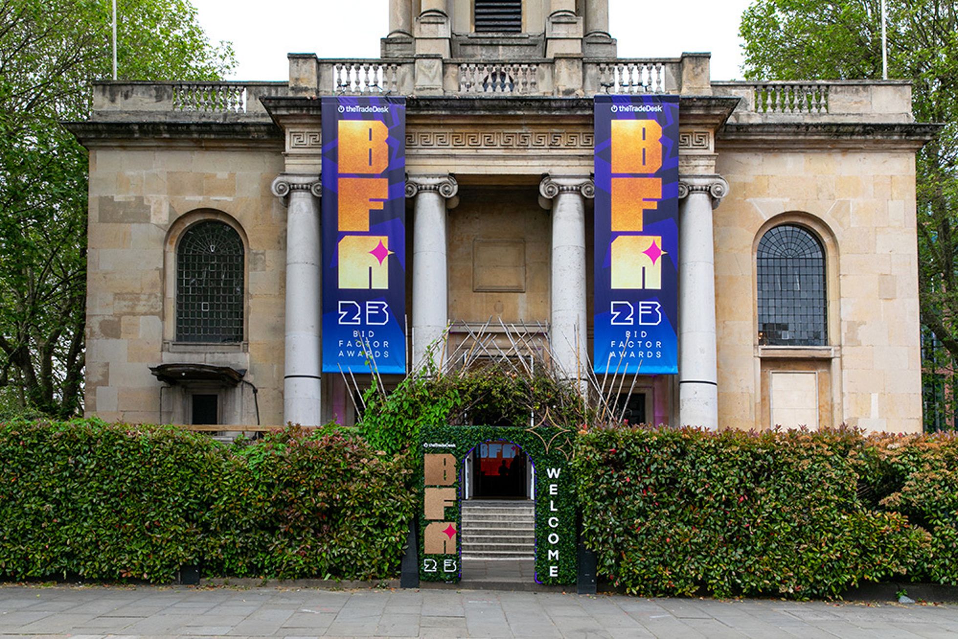 Historic building with two large event banners and greenery in front