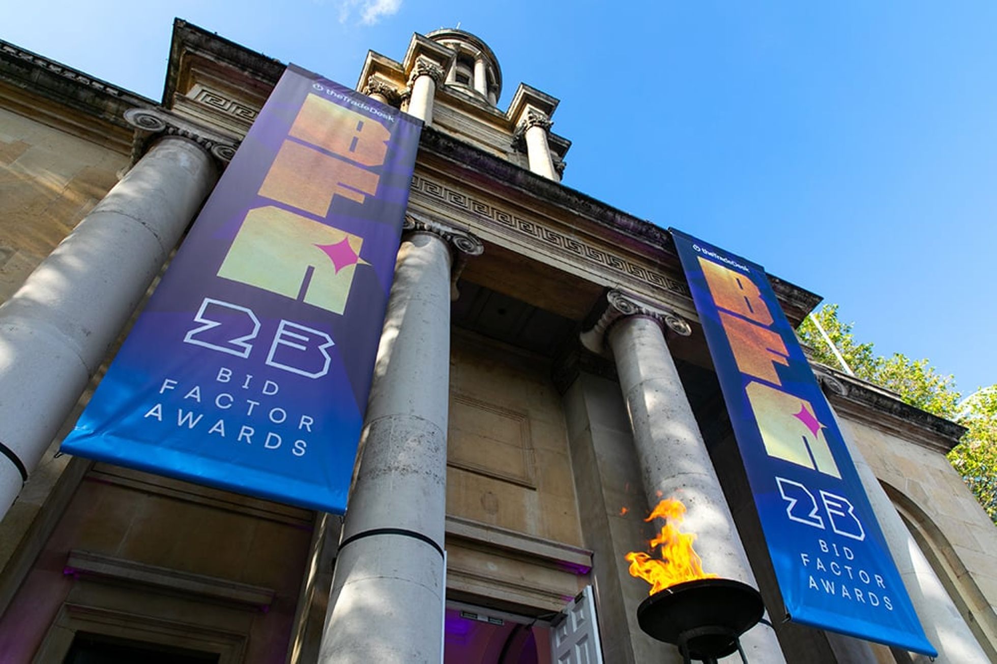 Historic building with two large event banners and greenery in front