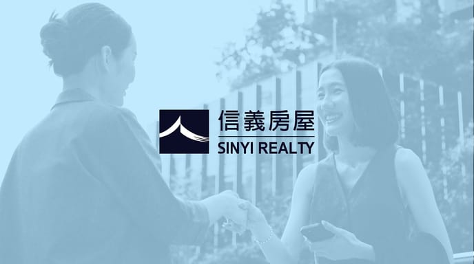 Two women smile and shake hands in front of a modern city building, overlaid with the Sinyi Realty logo and Chinese characters in the center of the image.