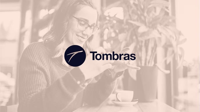 A smiling woman takes a photo of a receipt with her smartphone in a café, overlaid with a sepia filter and the Tombras logo in the center.