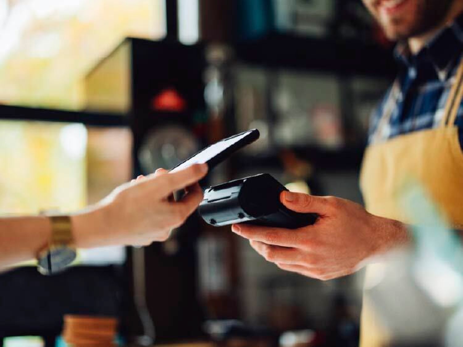 A hang tapping their mobile pay feature to a card reader in a store