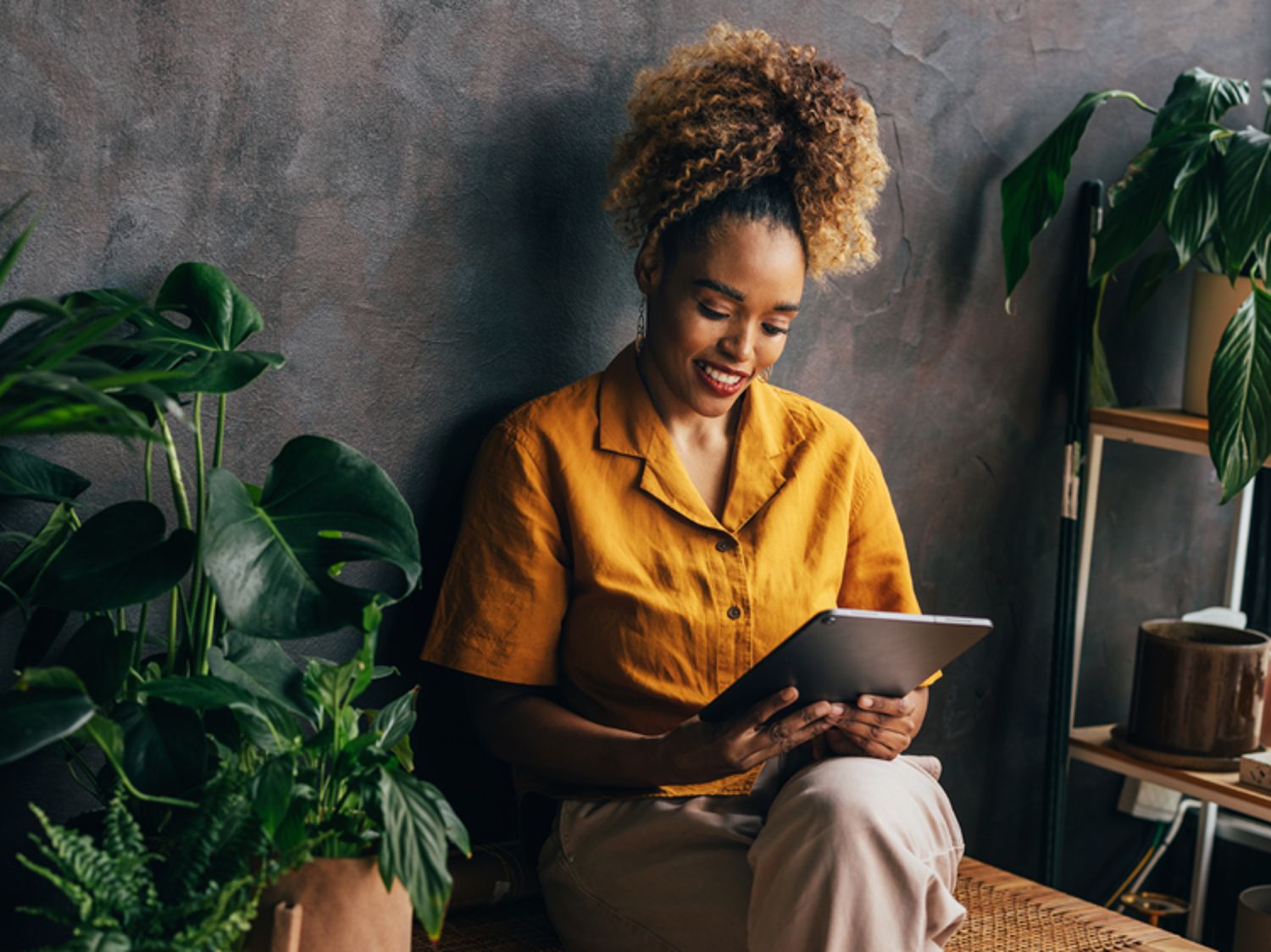 Woman in a yellow shirt sitting and looking at her tablet