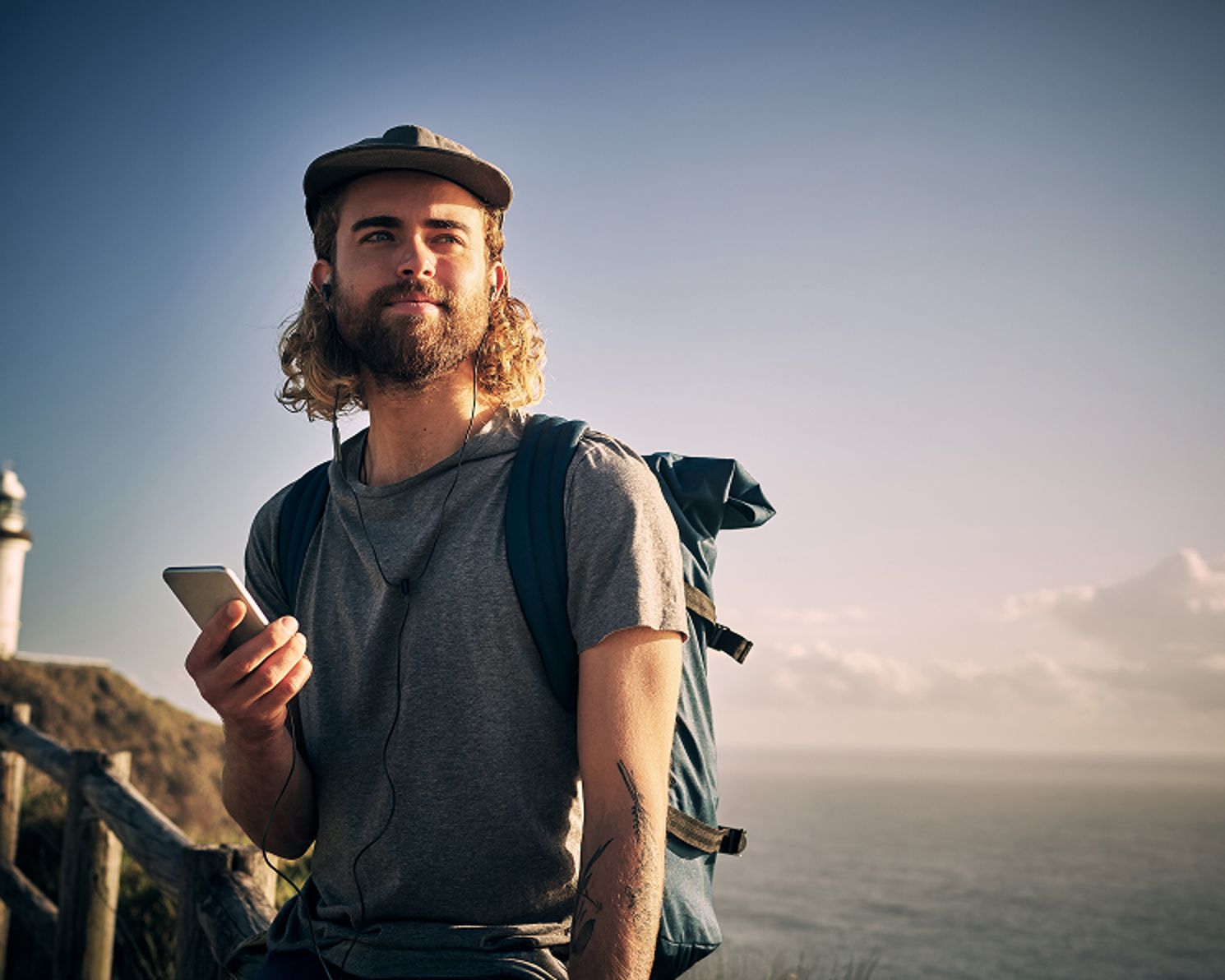 Man outside wearing a backpack while listening to audio from his phone