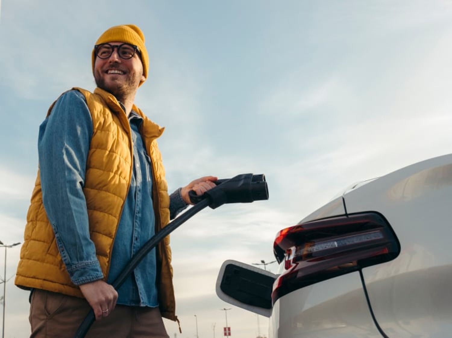 Image shows a man getting ready to charge his car. Audi, and PHD logos are featured at the top left corner of the image.