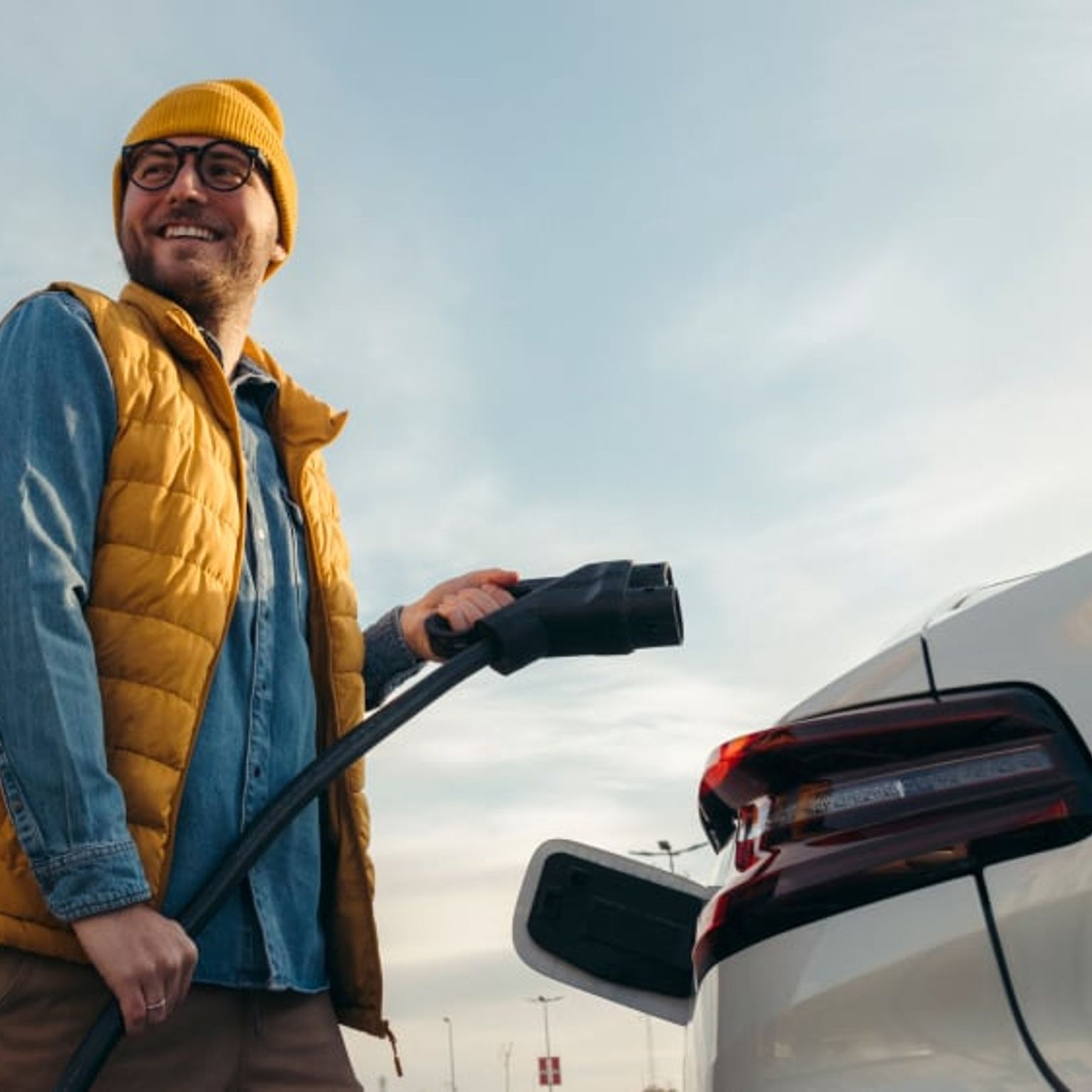 Image shows a man getting ready to charge his car. Audi, and PHD logos are featured at the top left corner of the image.