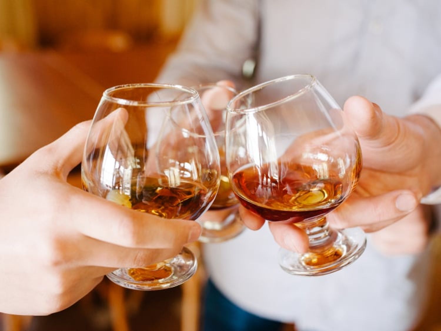 圖片中有三隻手各拿著一杯軒尼詩