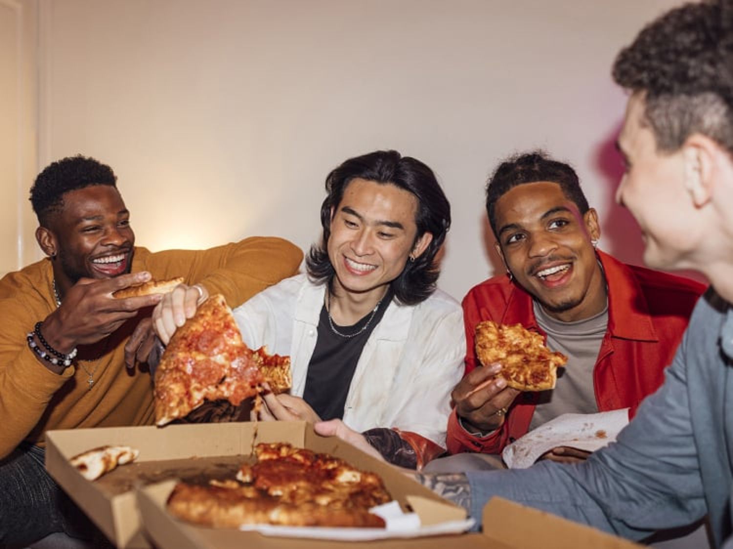 A group of friends laugh and eat pizza together