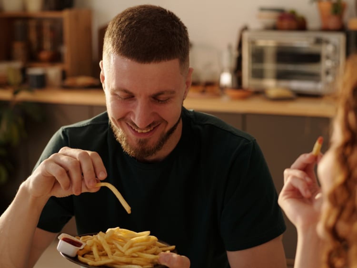 Image shows a person eating a basket of fries