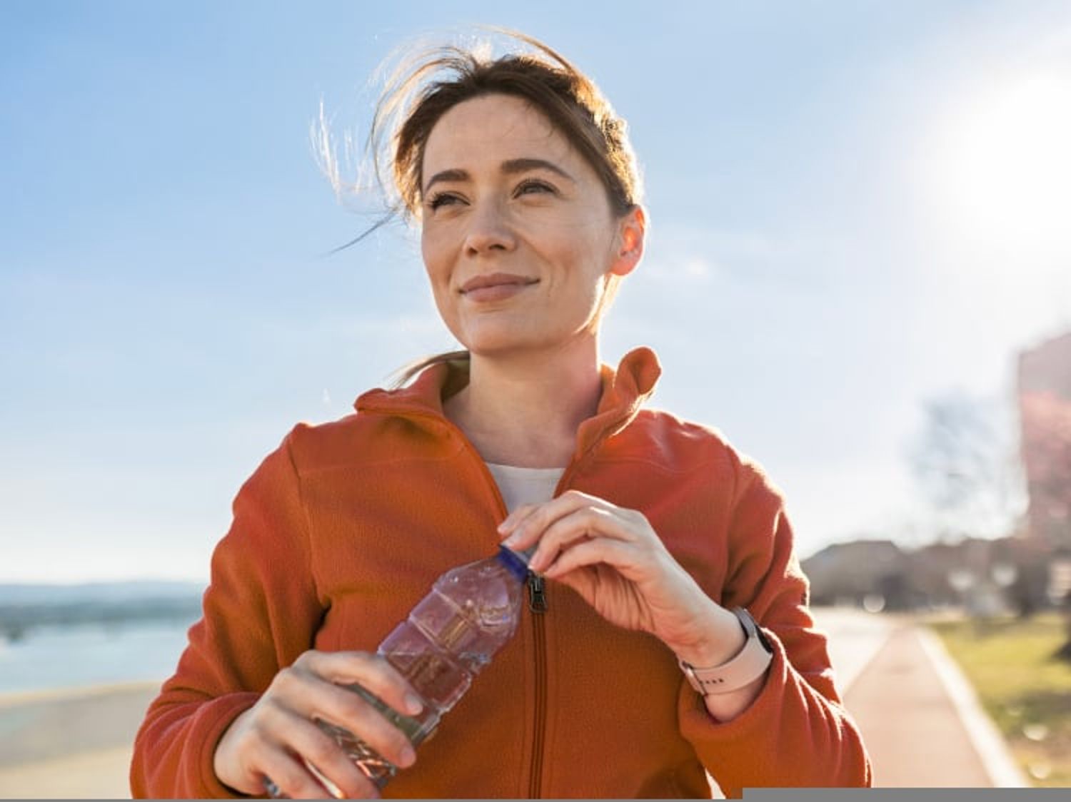 Image of a woman outside closing her water bottle and smiling
