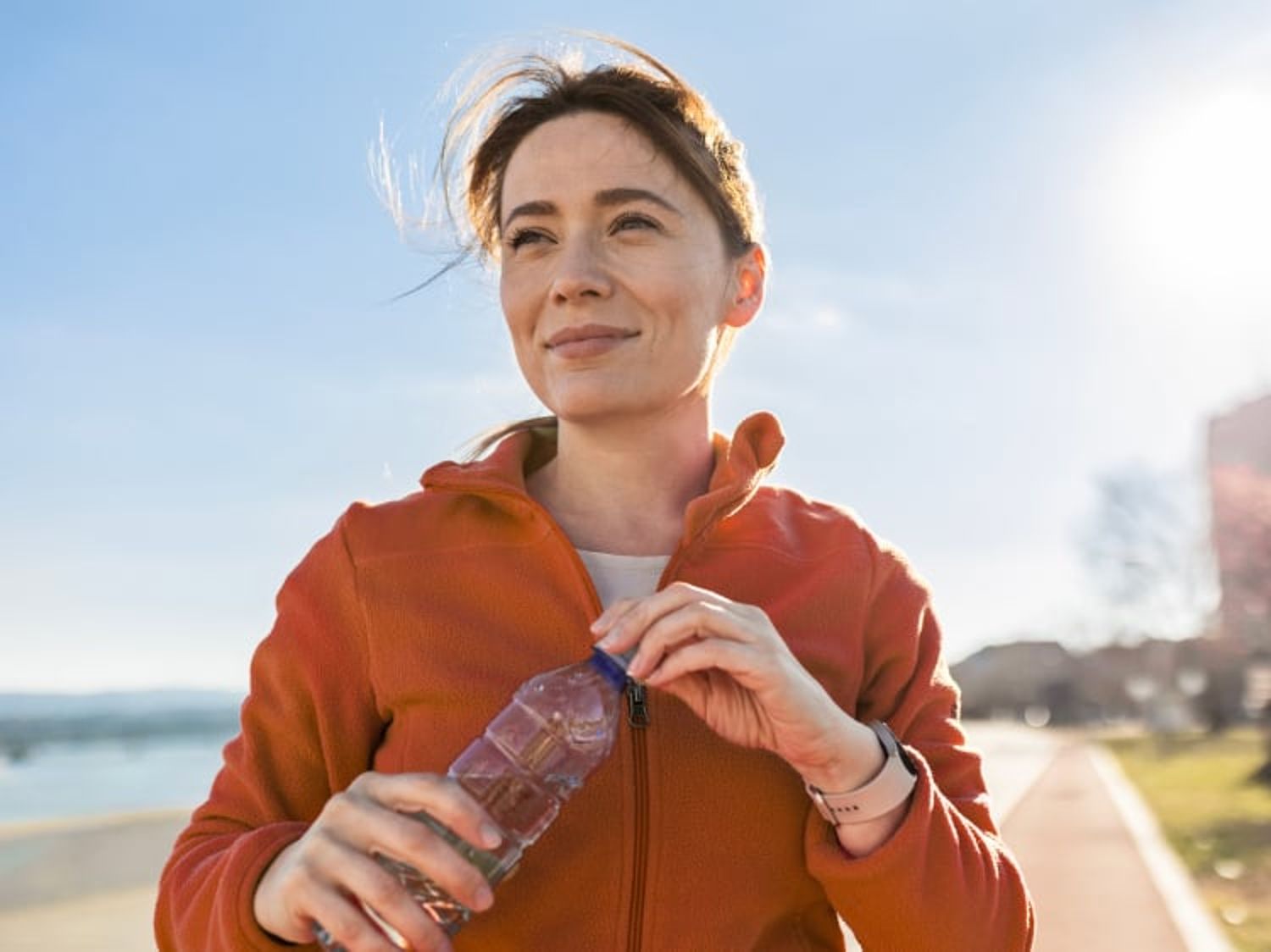 Image of a woman outside closing her water bottle and smiling