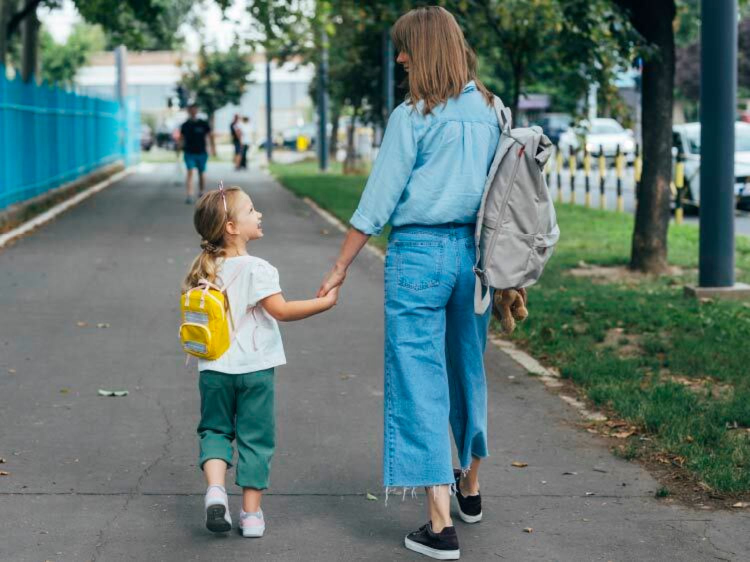 リュックサックを背負い、学校へ向かって歩く母子