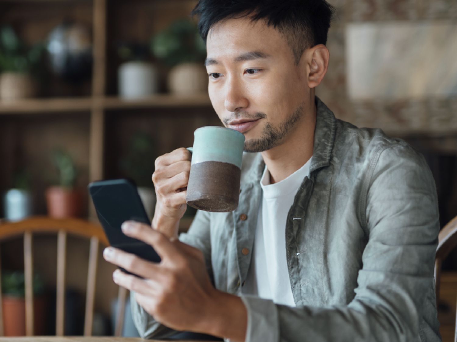 Man on his phone and drinking coffee