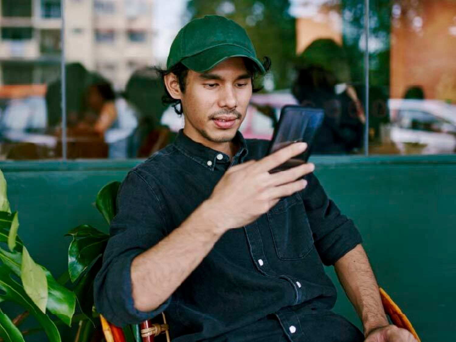 Man wearing a green hat, while staring at his phone