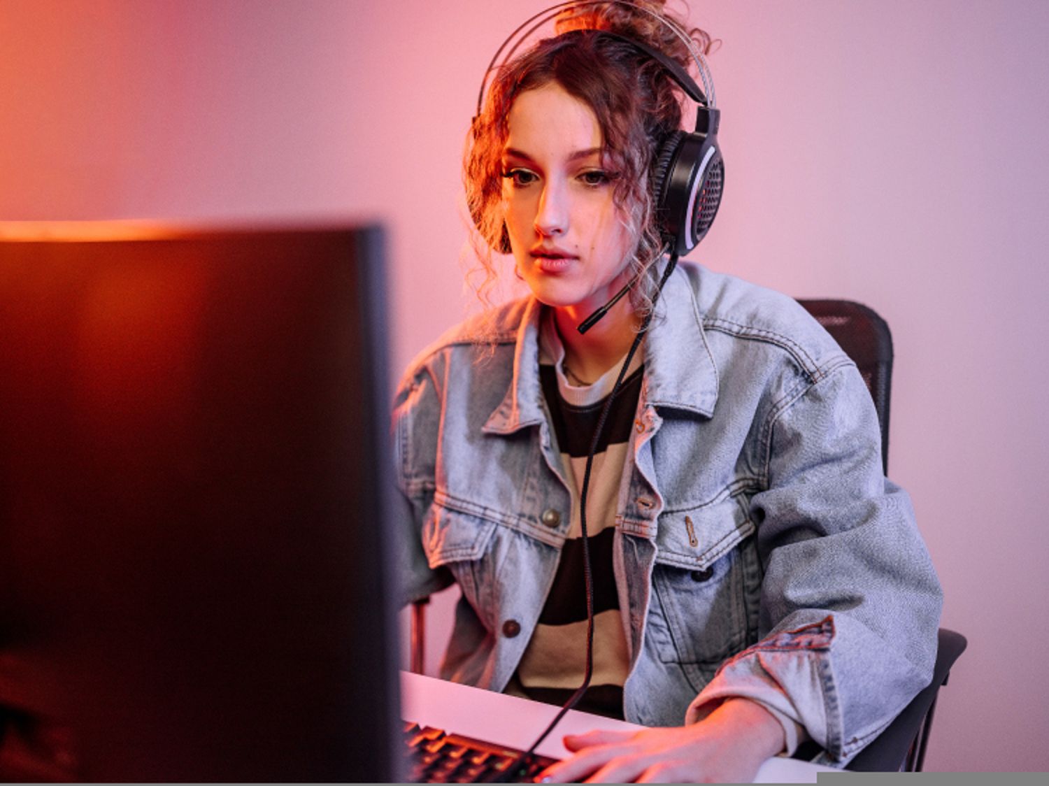 Woman gamer wearing headphones and looking concentrated at her computer