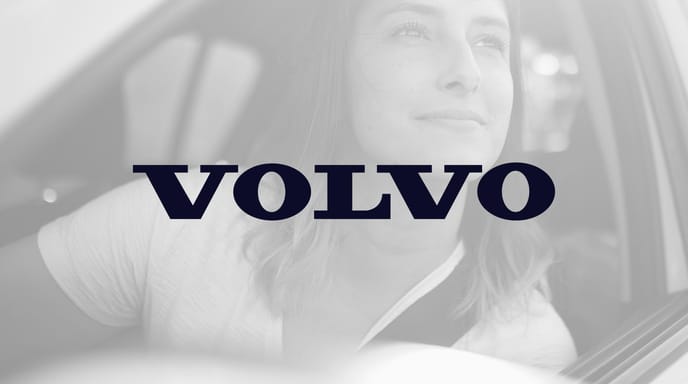 Woman smiling and looking out of the window of her Volvo SUV in black and white, with the Volvo logo in the center