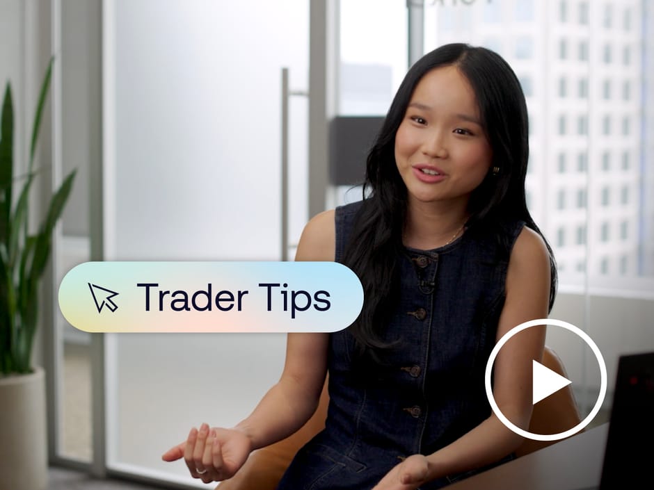 Woman sitting at a desk with a graphic of text saying "Trader Tips" and a play button placed over her