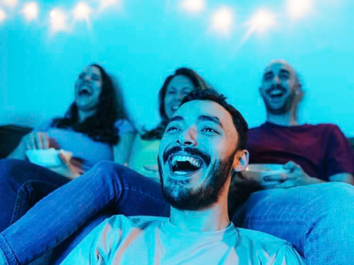 Image shows a group friends watching TV and laughing