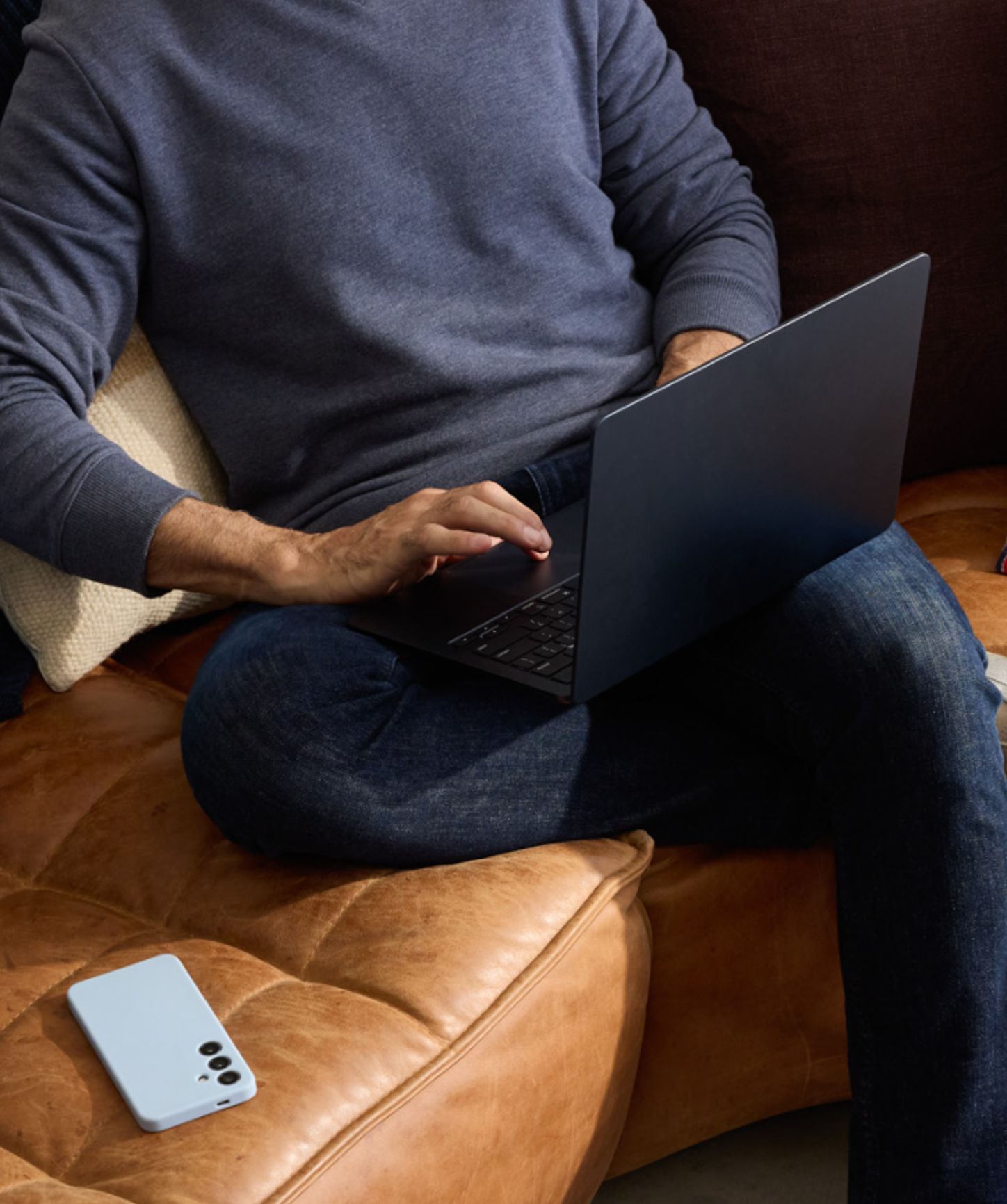 Person sitting on a sofa and working on their laptop