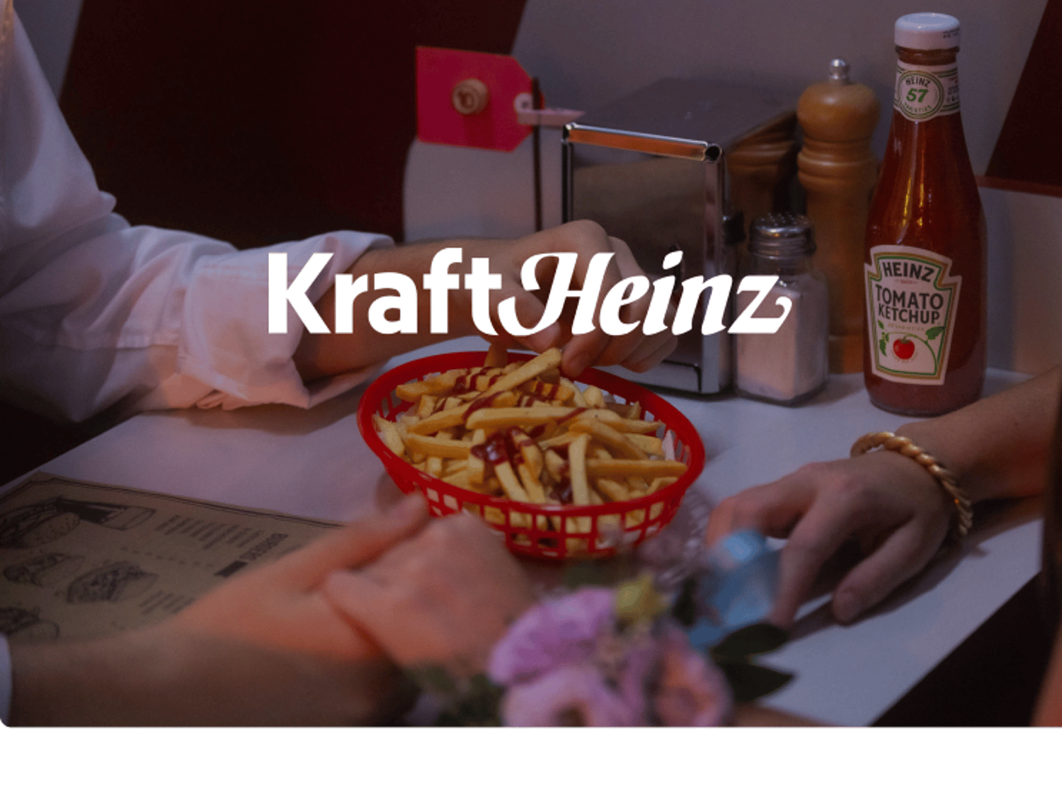 Kraft Heinz logo against a background image showing a couple holding hands while sharing a basket of fries