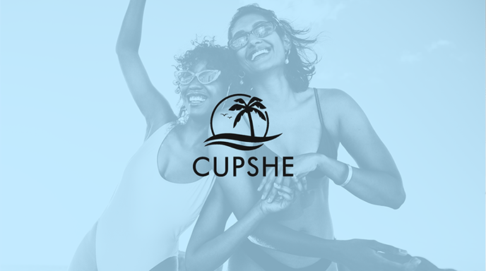 Two women in swimsuits and sunglasses laugh joyfully at the beach under a clear sky, overlaid with a blue filter and centered logo for Cupshe.