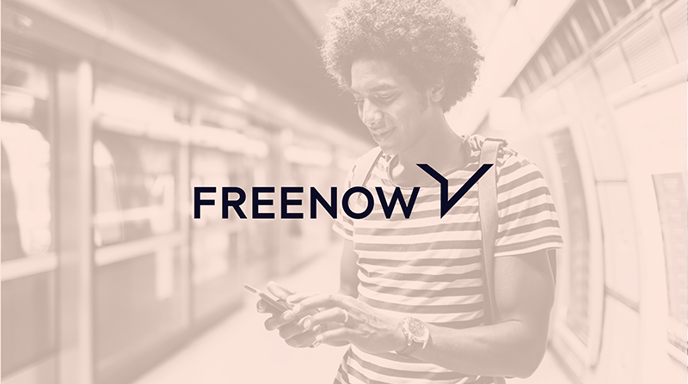 Man in a striped shirt, looking at his phone with an orange overlay and the FREENOW logo over top
