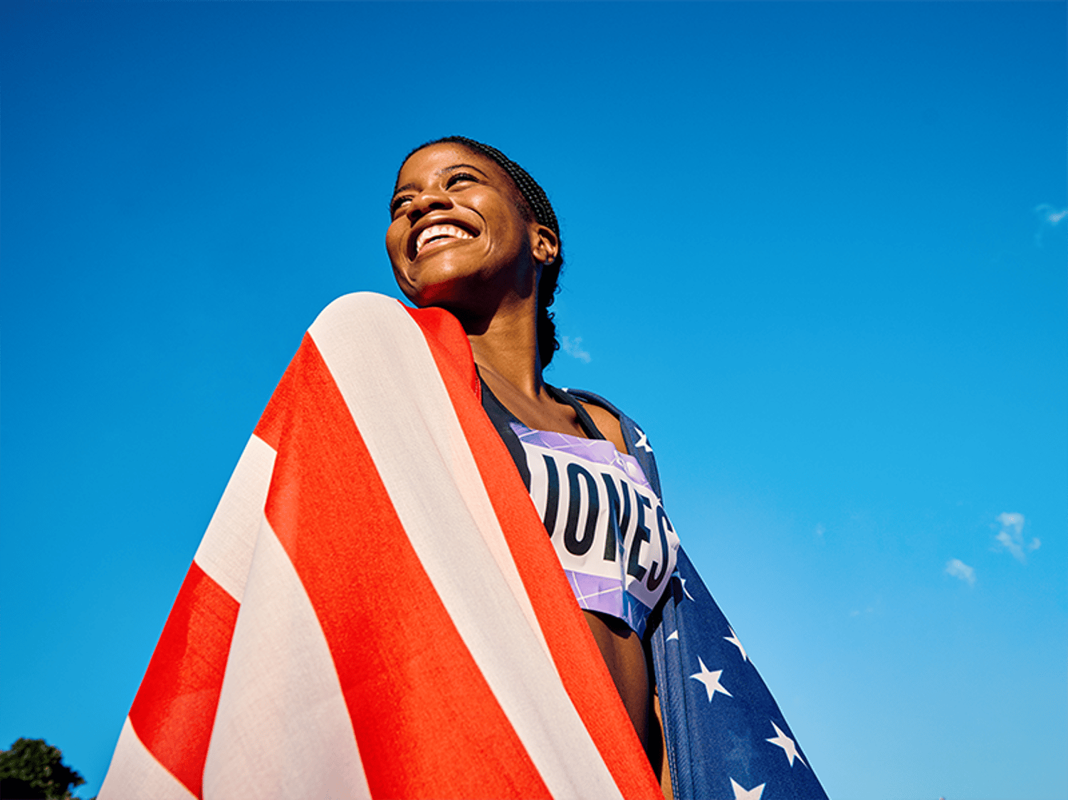 An olympian smiling and wrapped in the American flag