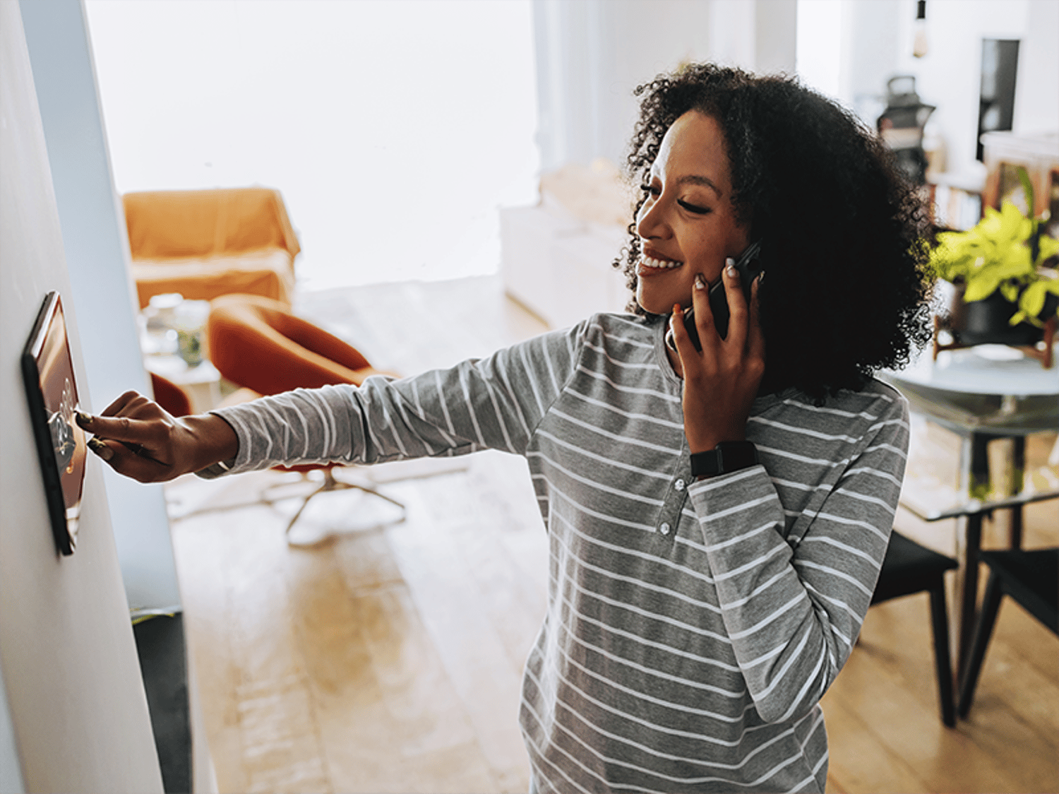 Woman speaking on a phone while clicking a wall unit