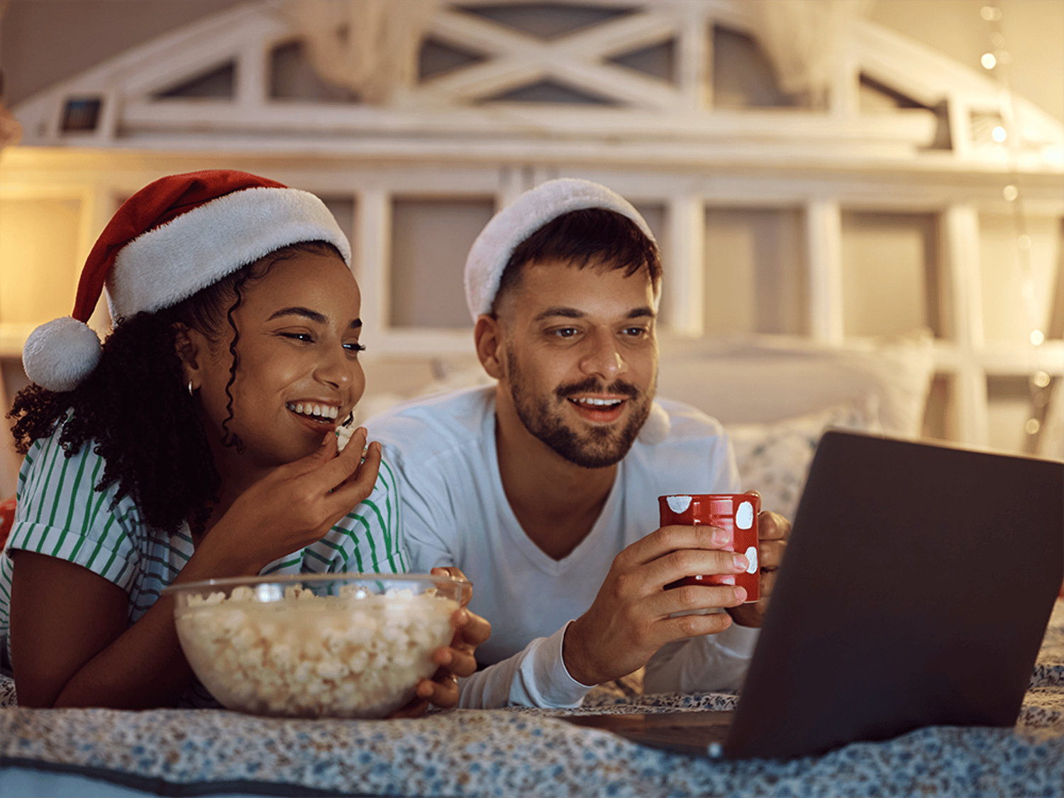 Image of a man and woman eating popcorn and smiling at a laptop