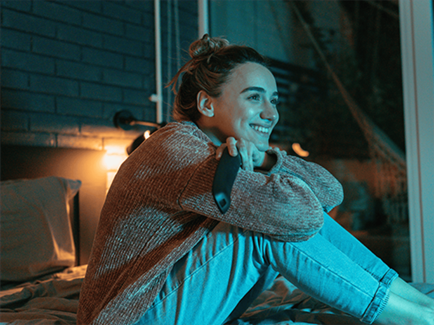 Woman sitting ans smiling while watching TV