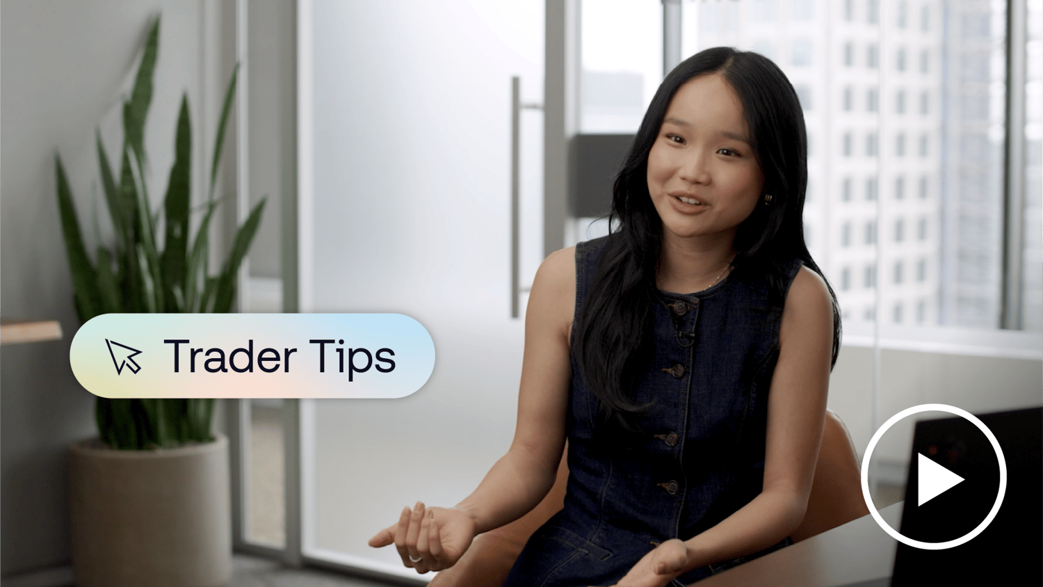 Candid image of a trader smiling at the camera while sitting at her desk with her laptop open. A banner on screen reads “Trader Tips."